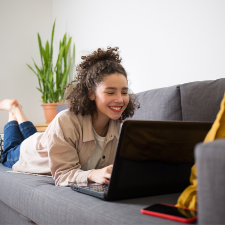 Woman lying on couch on her laptop thinking about a personal loan