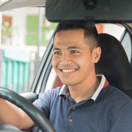 Man in blue shirt driving his car after securing vehicle finance.