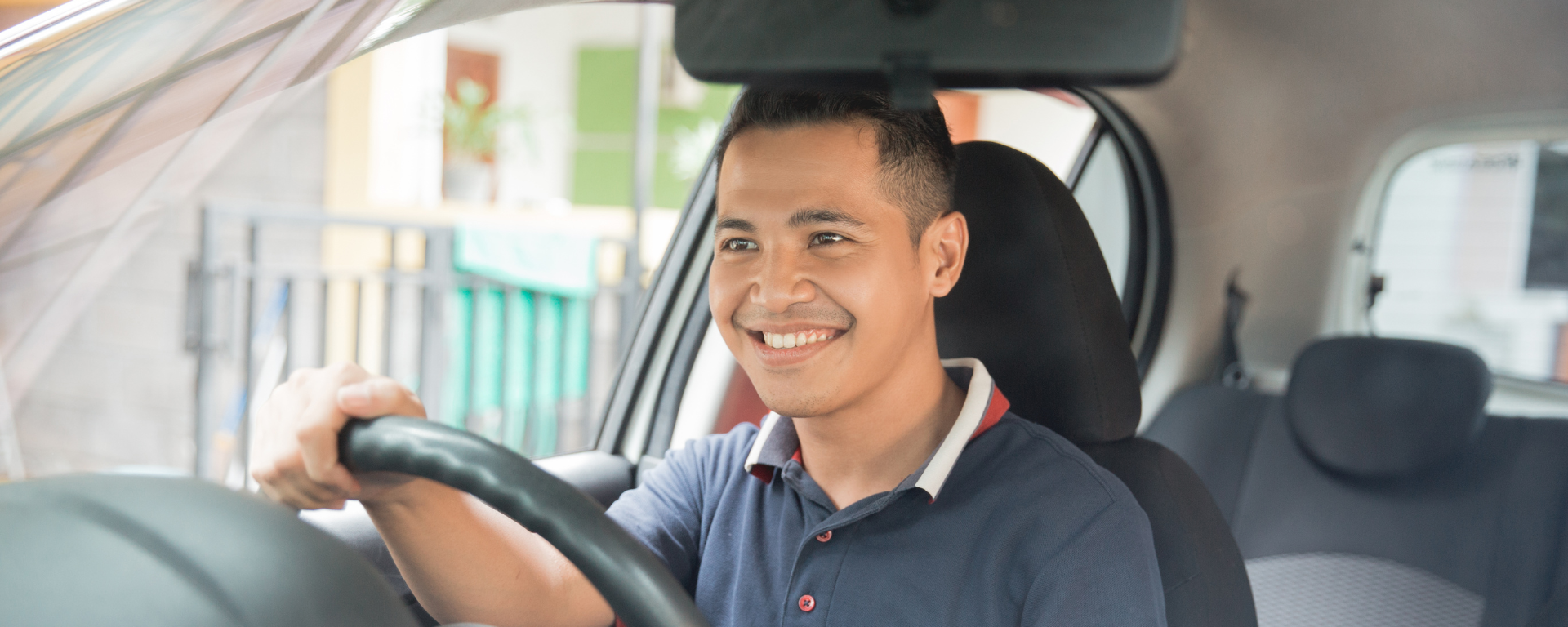 Man in blue shirt driving his car after securing vehicle finance.