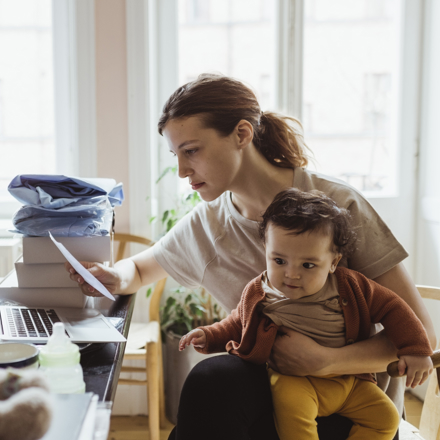 Woman sitting with baby looking at a bill thinking about a medical loan nz