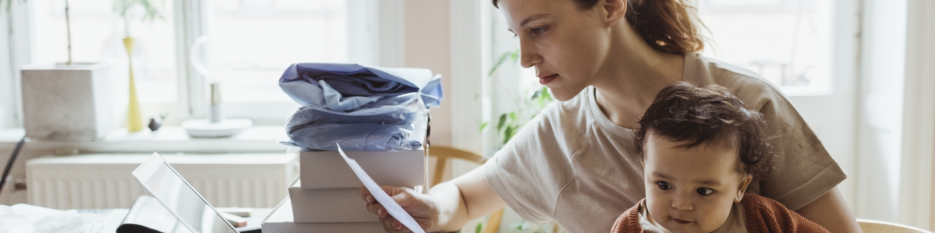 Woman sitting with baby looking at a bill thinking about a medical loan nz