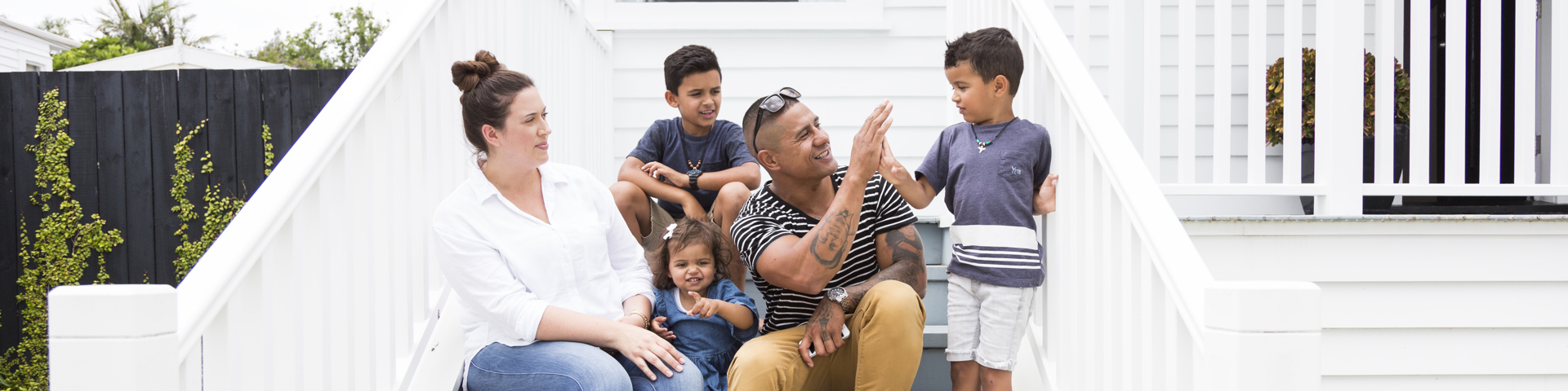 Family sitting on steps outside home, thinking about Life and Funeral Insurance